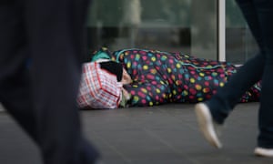 People walk past a rough sleeper on a London street.