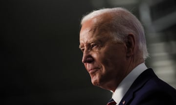 Joe Biden, lit from above and seen in profile, an older white man with white hair, wearing a dark suit.