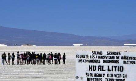 A sign against the exploitation of lithium is seen as tourists visit the Salinas Grandes salt flat.