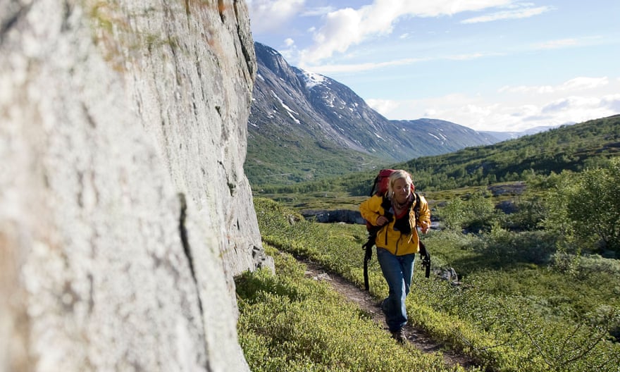 Female hiker with backpack walking on landscape against mountains, Norway
