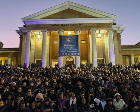 A large crowd of people gather in front of a university building