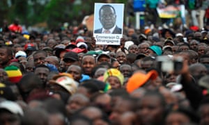 A person holds up a portrait of Emmerson Mnangagwa amid fellow protesters.