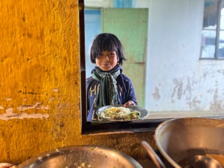 A boy stands at an opening holding a plate of food
