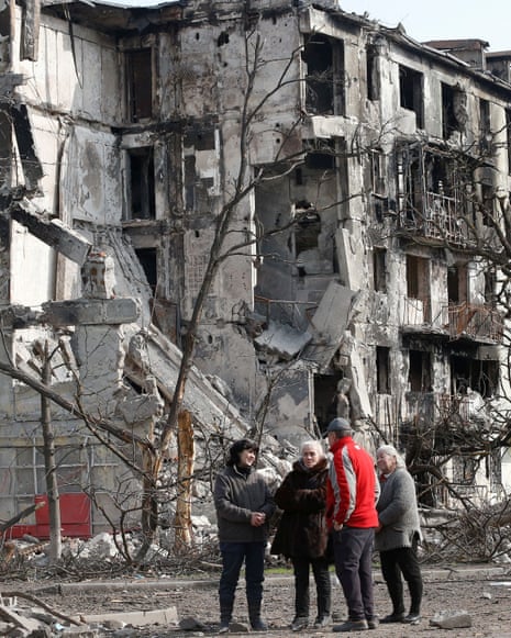 Local residents speak in front of a damaged block of flats in Mariupol