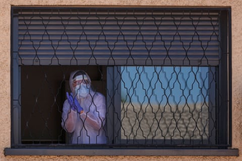 A member of the Military Emergencies Unit appears at a window during a disinfection in the Getafe suburb of Madrid on 25 March. 