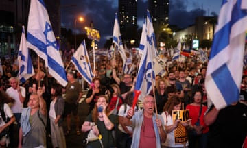 Masses of people chanting, marching and holding Israeli flags.