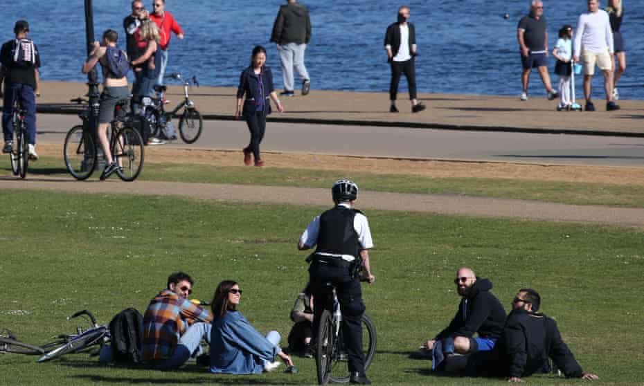 A police officer speaks to people relaxing by the Serpentine in Hyde Park, London, durng the lockdown in April. 