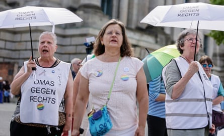 Women wearing bibs and carrying umbrellas that read ‘Omas gegen Rechts’.