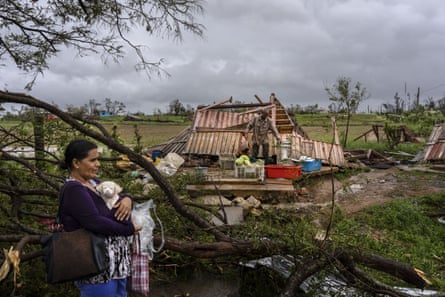 Woman holding dog staring out at the aftermath of hurricane