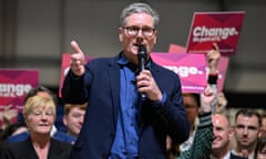 Keir Starmer speaks into a microphone. Onlookers hold aloft pink and purple placards that read: Change. Be part of it.'