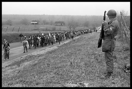 a man looking at people marching