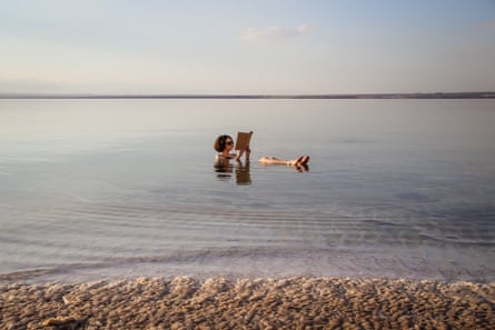 A girl floating in the Dead Sea in Jordan, reading a book