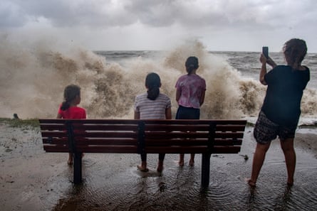 A family watch the storm roll in at Holloways Beach in Cairns.