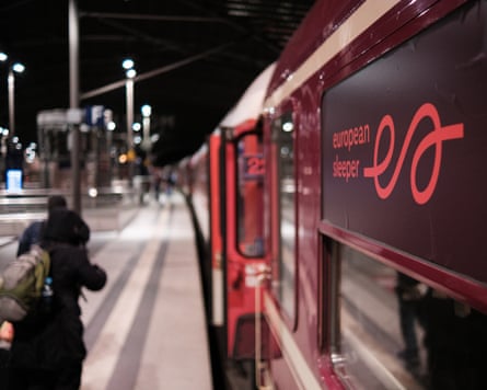 Sleeper train at night picks up passengers on a platform