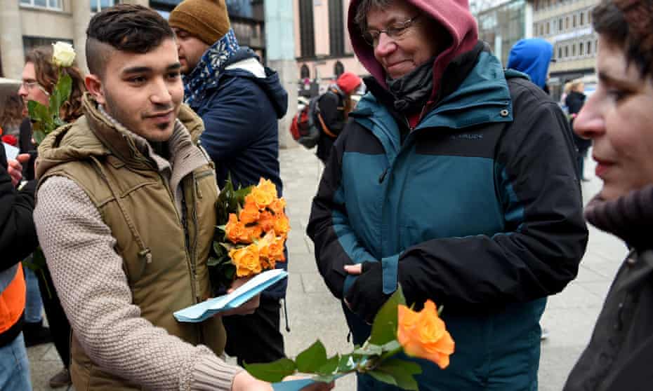 Refugees from Syria present flowers to passers-by in Cologne. Unease is growing among German MPs over the nation’s ability to absorb millions of newcomers. 