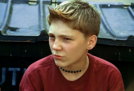 Paul Dano in red T-shirt with necklace and pierced ear
