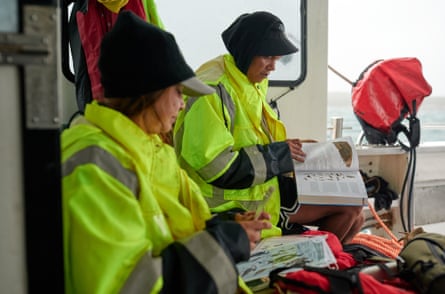 Two rangers on a boat study books about birds