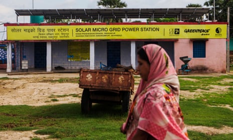 A woman walks past a solar power microgrid power station in the village of Dharnai in Jehanabad, Bihar, India.