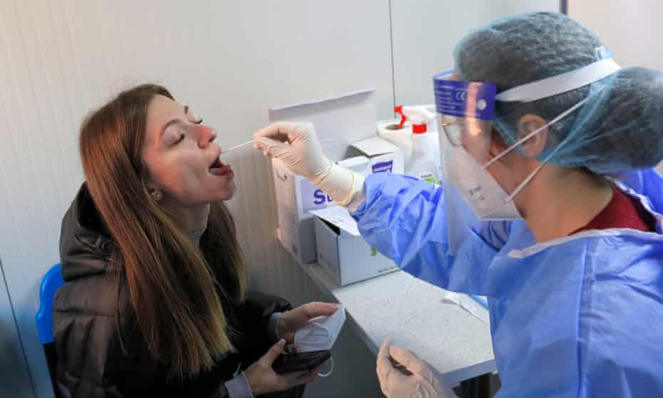 A hospital staff member wearing fully protective suit takes a saliva sample from a woman at the National Institute of Pneumology 'Marius Nasta', in Bucharest, Romania