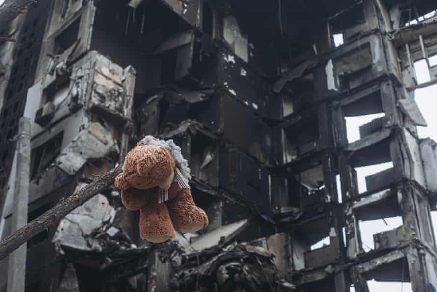 A teddy bear hanging from a tree in front of a building bombed by the Russian army in Borodyanka.