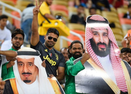 Fans hold aloft cardboard cutouts of Saudi Arabia’s King Salman and the Saudi Crown Prince Mohammed bin Salman