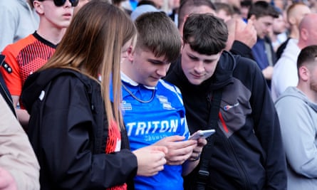 Birmingham fans check the scores from elsewhere on their phones