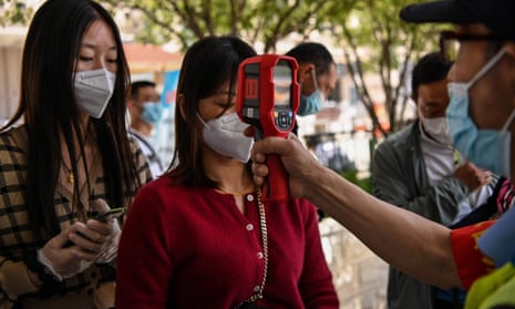 A worker wearing checks passengers’ temperatures and a health code on their phones at Hankou railway station in Wuhan.