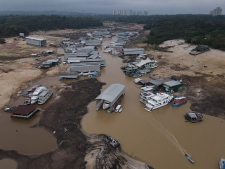 Boats line a narrow channel of water with wide banks of mud on either side