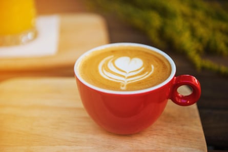 Red coffee cup in a summer day with flowers in background