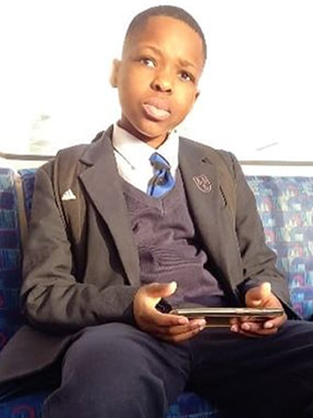 Daniel Anjorin wearing a dark school uniform sitting on a tube train