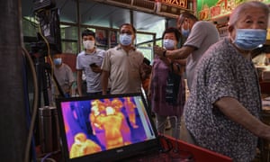 Shoppers have their temperature checked by thermal imaging at the entrance to a local market in Beijing.