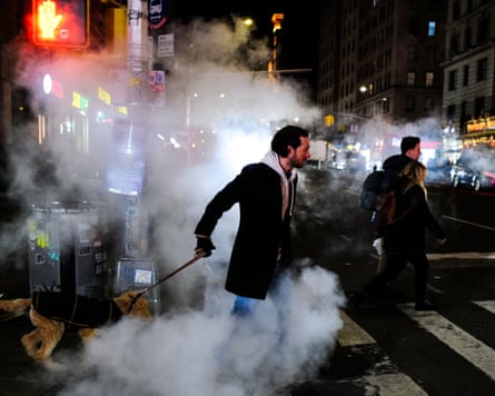 A man walks his dog late at night in New York City, surrounded by smoke