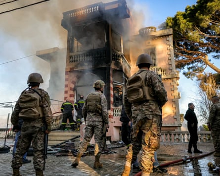 Soldiers standing in front of a burning two-storey building