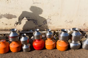 A woman’s shadow falls behind a queue of pots, laid out by residents of the city of Latur