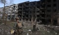 A Ukainian police officer walks past a destroyed residential building in Ocheretyne.