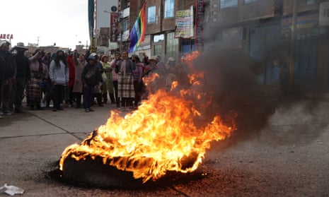 Anti-government demonstrators stand next to a burned tire, after Peruvian lawmakers failed to bring forward elections.