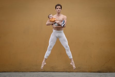 Ballet dancer Roberto Rodriguez pictured jumping while cradling his young son.