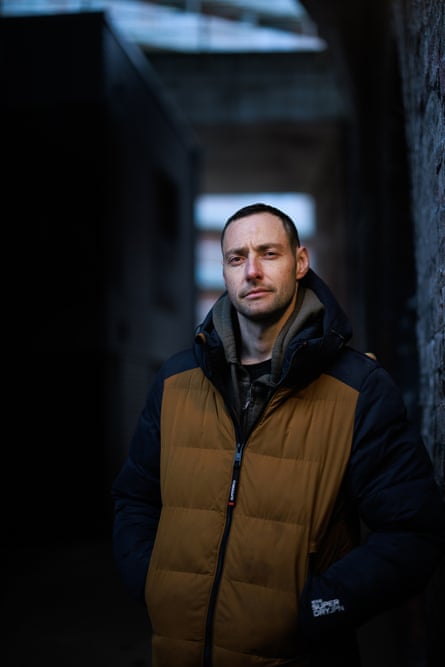 A man leaning against a brick wall with a new-build home in the background