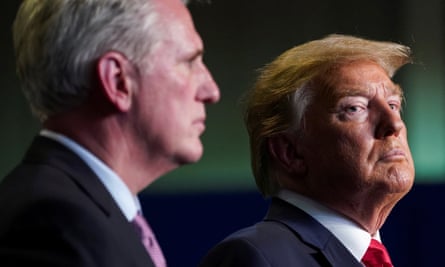 A closeup of two middle-aged white men wearing suits. McCarthy is on the left, slightly blurry in the foreground, and Trump is on the right, in focus and looking stern.