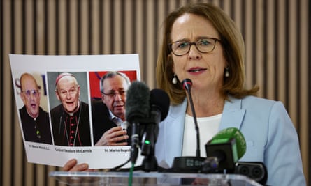 Anne Barrett Doyle holds up printed pictures of Marcial Maciel, Theodore McCarrick and Marko Rupnik.