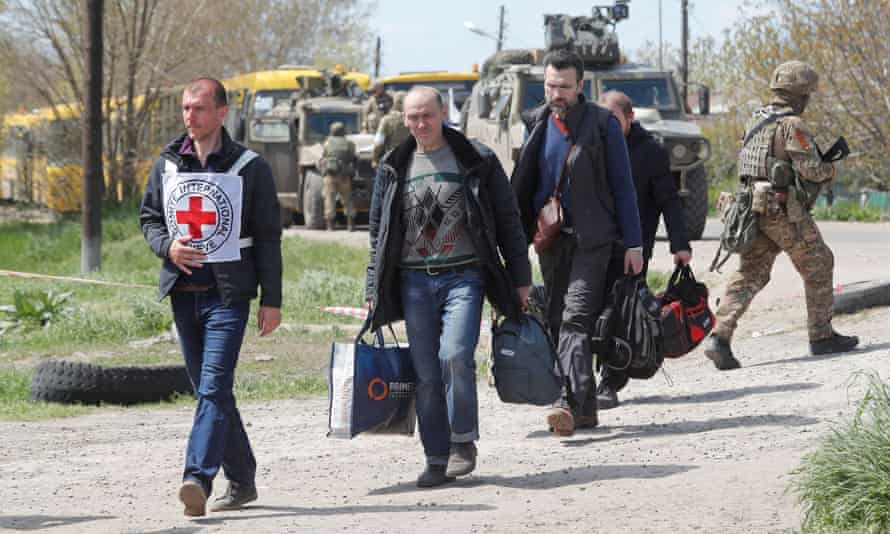 Civilians who left the area near Azovstal steel plant in Mariupol walk accompanied by a member of the International Committee of the Red Cross (ICRC) at a temporary accommodation centre in the village of Bezimenne in Russian-separatist eastern Ukraine. REUTERS/Alexander Ermochenko