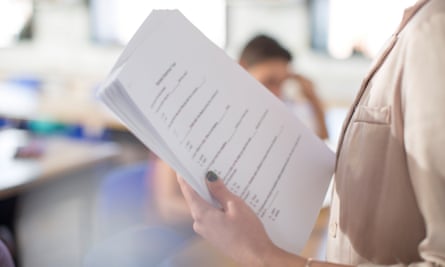 A teacher holds a pile of papers in a classroom