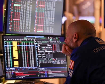 A trader on the New York Stock Exchange looks at screens.