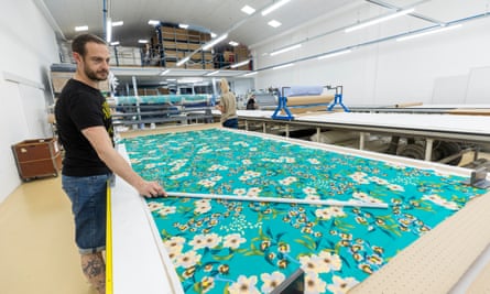 Factory worker with roll of fabric spread out ready for cutting