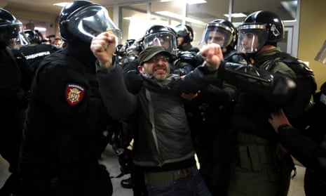 Serbian riot police scuffle with a protester who invaded the state TV building during an anti-government demonstration.