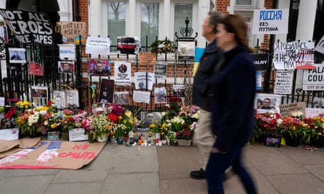 People walk past railings near the Russian embassy in London decorated with flowers and banners in memory of Alexei Navalny, the late Russian opposition leader.