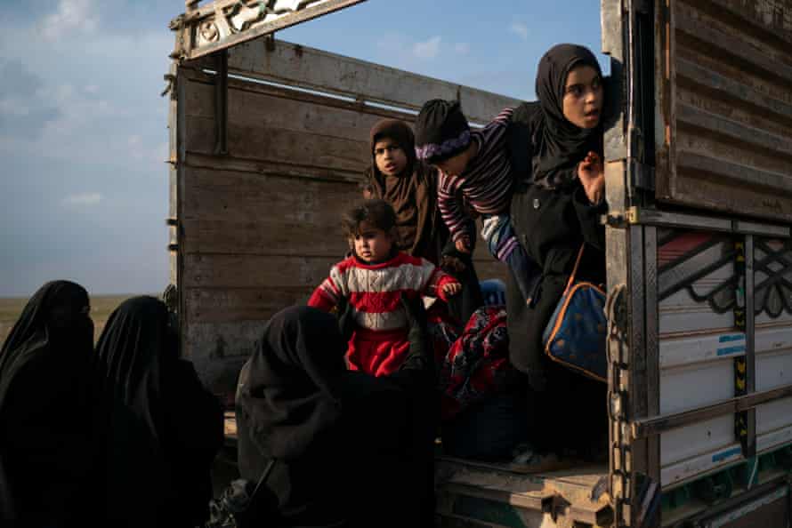 Women and children leave the back of a truck, part of a convoy evacuating hundreds out of the last territory held by Isis militants in Baghuz, eastern Syria