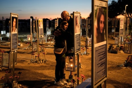 Benny and Maggy Solomon hug as they stand among the display of victims at the site of the Nova festival.