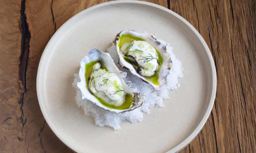 Two oysters in their shells in sauce on a round white plate