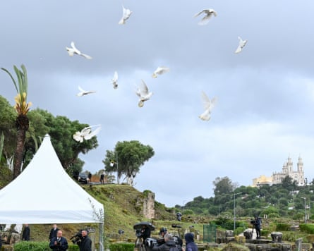 Birds flying in the sky above marquees with people gathered underneath